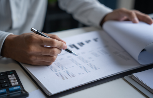 Person sieht sich Zahlen und Statistiken auf Papier an