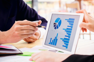 Zwei Personen beraten mit einem Tablet und Statistiken