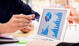 Zwei Personen beraten mit einem Tablet und Statistiken