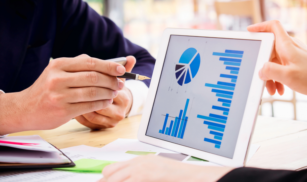 Zwei Personen beraten mit einem Tablet und Statistiken